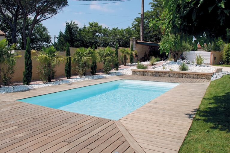 Piscine en béton rectangulaire avec terrasse bois dans un jardin paysager du Morbihan