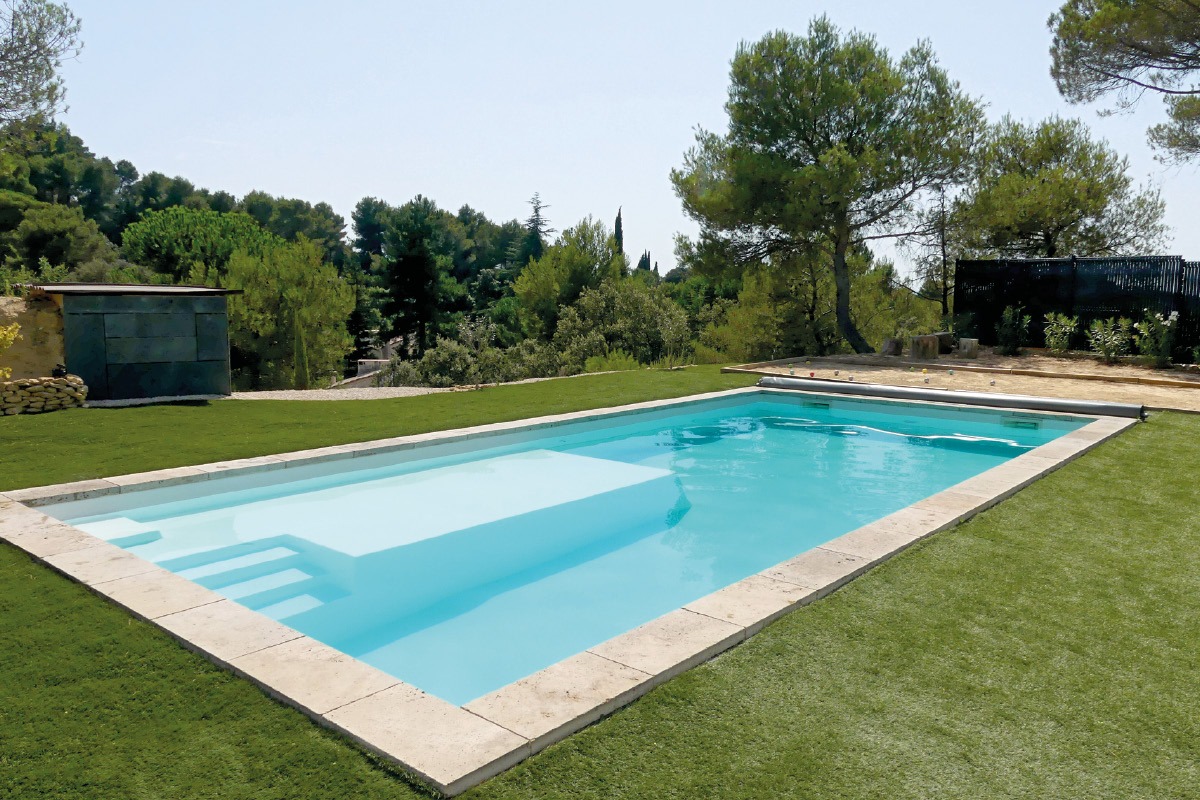 Piscine rectangulaire avec escalier d'angle et pelouse dans un jardin en Provence